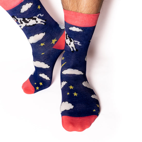 Just like in the nursery rhyme when the cow jumped over the moon. A navy base sets the scene of a fantastical, fun, star-filled night sky. Cows. On Socks. We know!  Available in US Men’s 4-8 and 8-12. Soft. Strong. Sustainable. Comfortable. Incredible Socks. Cow jumping over the moon socks.